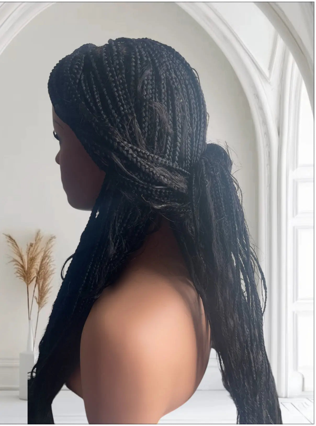 Side profile of a person with long black human-hair boho goddess medium braids in a low ponytail